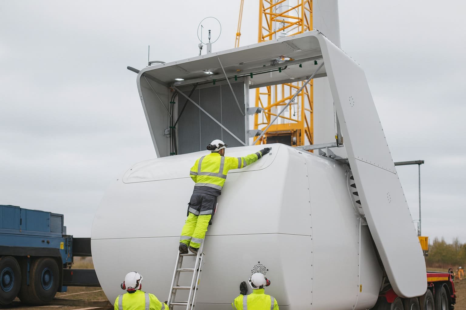 Techniker sichern die Gondel einer Windkraftanlage während der Verladung mit Kran – kontrollierte Bewegung und präzise Abstimmung Techniker sichern die Gondel einer Windkraftanlage während der Verladung mit Kran – kontrollierte Bewegung und präzise Abstimmung