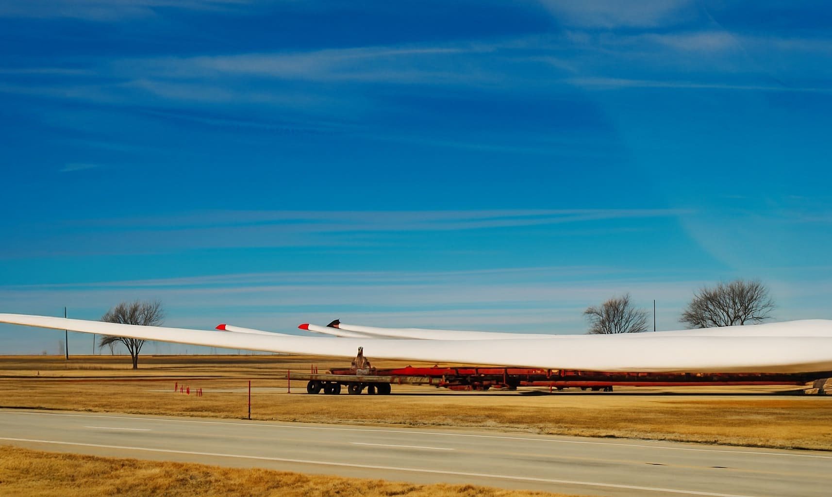 Spezialtransport eines Rotorblatts für eine Windkraftanlage – auf Teleskopaufliegern über Landstraße